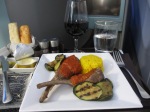 white plate of lamb cutlets, grilled vegetables and rice. Etihad business class