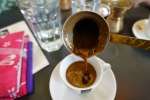 Pouring Greek coffee into a cup and saucer