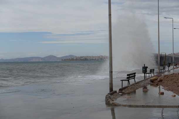 waves crashing against a breakwater with two benches