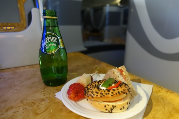 plate of bagel, sandwich and bottle of Perrier