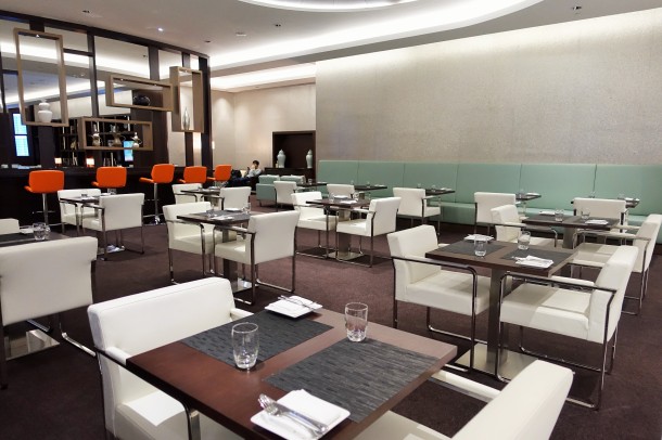 white chairs and dark square tables in the Etihad lounge in Abu Dhabi
