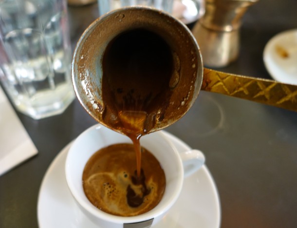 Greek coffee poured from a traditional metal pot